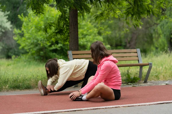 Two Attractive Young Girls Stretching Together While Talking Each Other — стоковое фото