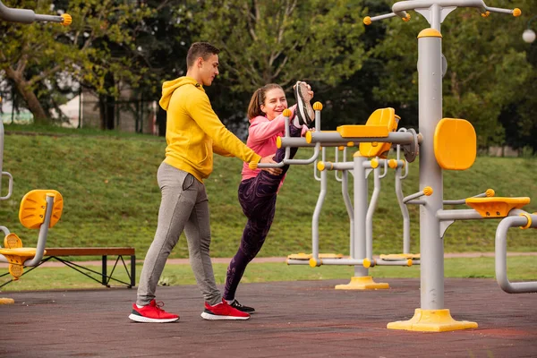 Fešák Chlap Pomáhá Své Přítelkyni Protáhnout Nohy Mříže Zatímco Směje — Stock fotografie