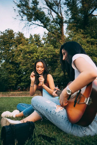 4人の素晴らしいと美しい女の子はギターを演奏しながら一緒に素晴らしい時間を過ごしています — ストック写真