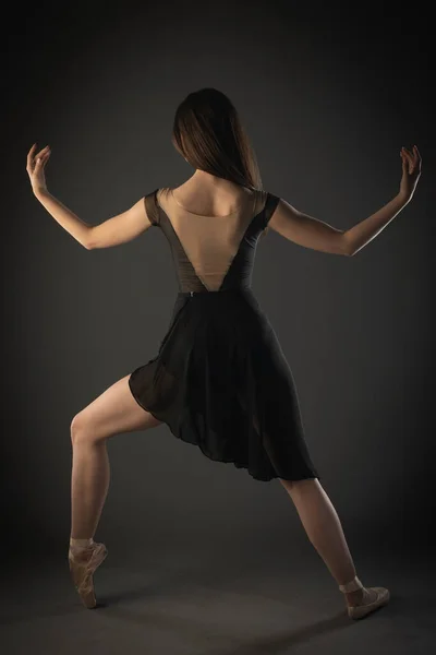 Elegancka Balerina Szpiczastych Butach Wykonuje Asymetryczną Baletową Pozę Tyłu Studia — Zdjęcie stockowe