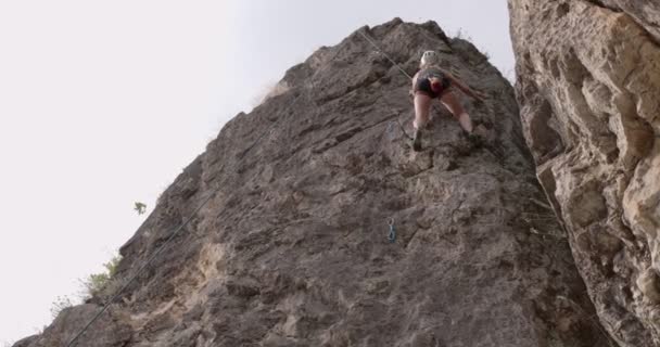 女性は大きな岩を登りながら手を差し伸べています — ストック動画