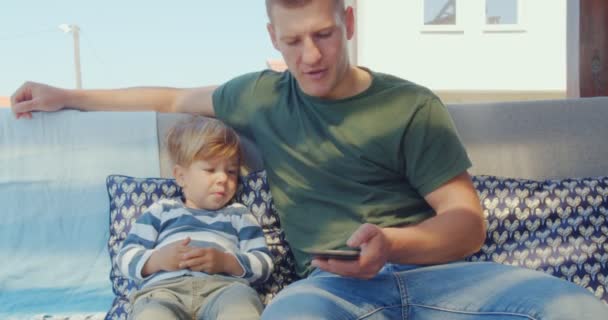 Jóképű Erős Apa Tartja Fiát Miközben Rajzfilmeket Néz Telefonban — Stock videók