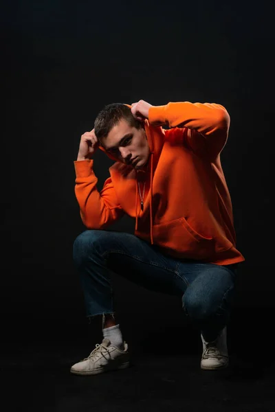 Man Model Zitten Vloer Poseren Oranje Sport Hoodie Geïsoleerd Een — Stockfoto