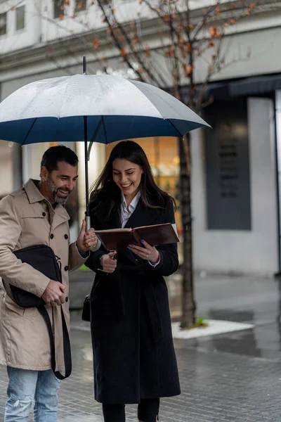 两个迷人美丽的商人一边微笑着一边说话 一边站在雨中 — 图库照片
