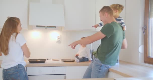 Tanto Padre Como Niño Apuntan Sartén Mientras Madre Está Cocinando — Vídeo de stock