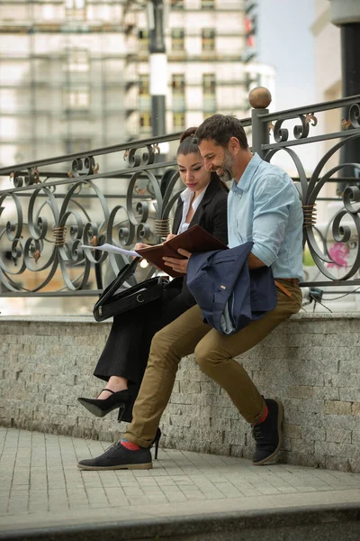 Dos Empresarios Urbanos Sonríen Miran Los Planos Mientras Están Sentados —  Fotos de Stock