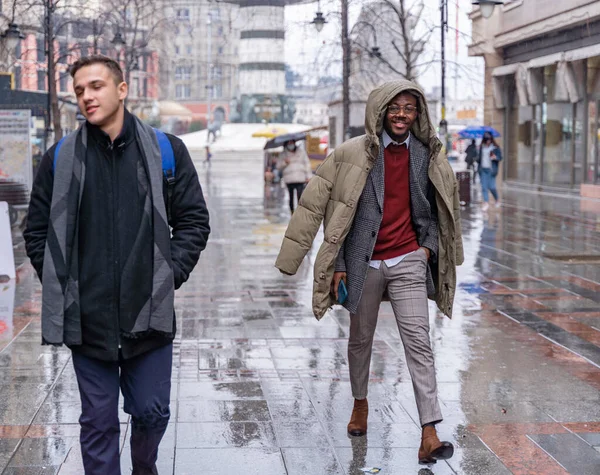 2人のハンサムで魅力的なビジネスマンが雨の中を歩いていると笑顔 — ストック写真