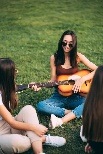 Chuda Piękna Młoda Dziewczyna Uśmiecha Się Gra Gitarze Siedząc Trawie — Zdjęcie stockowe