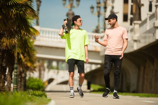 Two male friends are walking together while talking about something