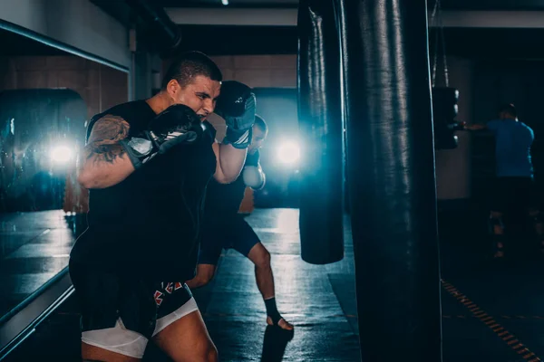 暗い背景にフィットネスジムで若い男運動選手ボクシングのトレーニング ハード運動選手のトレーニング キックボクシングの概念 — ストック写真