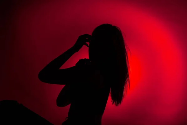 스튜디오에 앉아서 포즈를 취하는 소녀의 놀랍고 어두운 실루엣 — 스톡 사진
