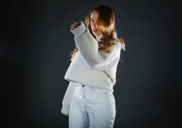 黒の背景に白いセーターと白いジーンズを着て長い髪の若い女性の肖像画 — ストック写真