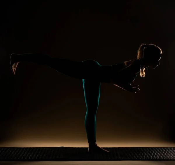 Silhouette of attractive and beautiful girl is doing a yoga pose