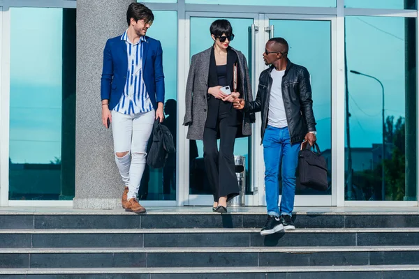 オフィスビルの外を歩いている間にビジネスを議論する正式な摩耗の若い現代多民族の人々 — ストック写真