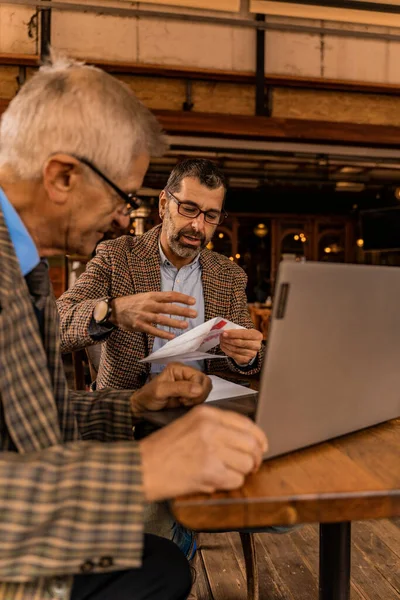 Δύο Ανώτεροι Επιχειρηματίες Κοιτάζουν Κάτι Λογαριασμούς Και Χαμογελούν Στο Καφέ — Φωτογραφία Αρχείου