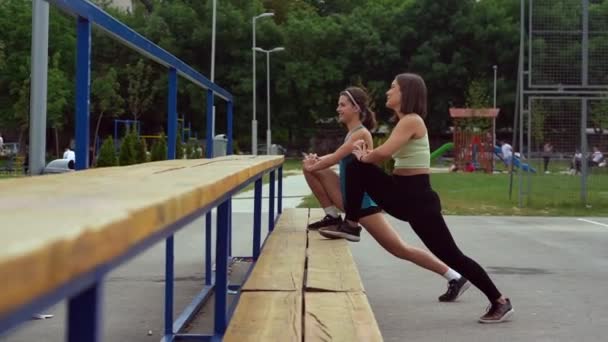 Twee Aantrekkelijke Mooie Meisjes Strekken Zich Uit Bank Terwijl Lachen — Stockvideo