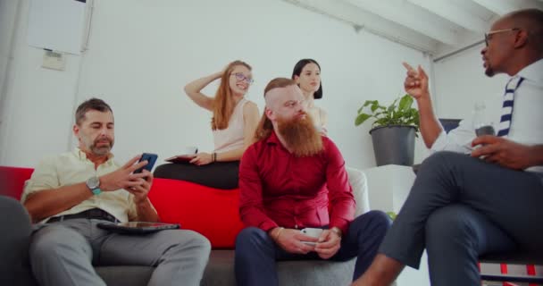 Група Багаторасових Співробітників Розмовляють Про Свою Каву Під Час Сидіння — стокове відео