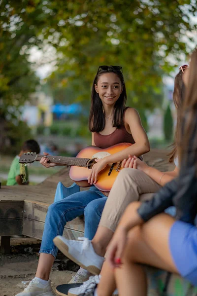 美丽的女孩一边在公园里玩吉他 一边笑着享受着自己的时光 — 图库照片