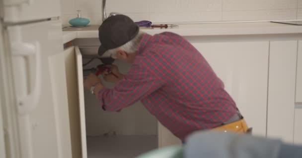 Senior Plumber Fixing Kitchen Sink — Stock Video