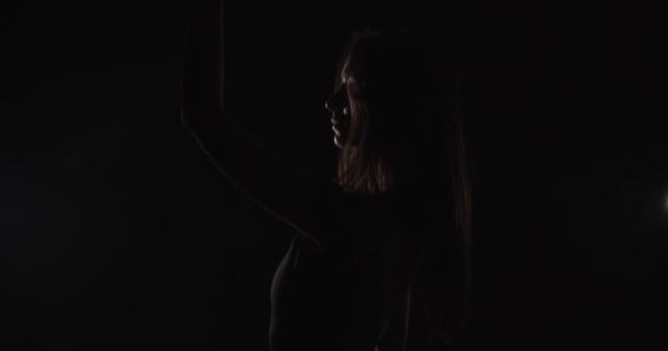 소녀가 어두운 배경의 스튜디오에서 춤추고 실루엣 — 비디오
