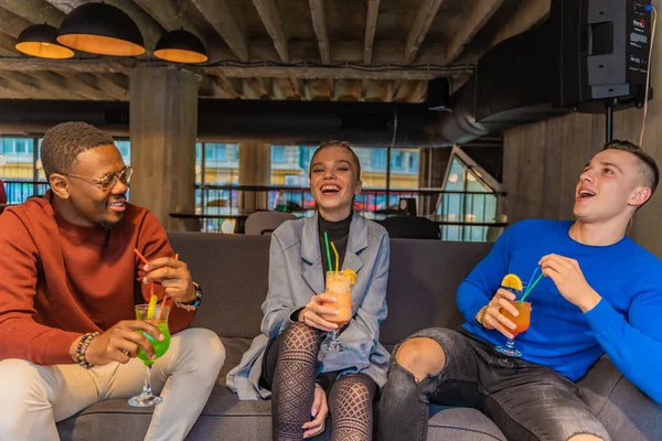 Três Amigos Multirraciais Estão Bebendo Suas Bebidas Enquanto Riem — Fotografia de Stock