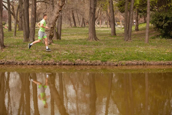 強力なスポーツマンは 草の上に水の横にある — ストック写真