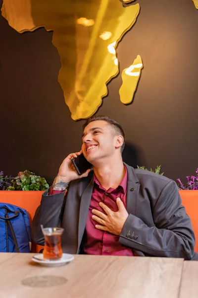 魅力的でハンサムなビジネスマンは座っている間彼の助けを借りて彼の電話で話しています — ストック写真