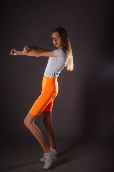 Красивая Спортивная Девушка Короткими Оранжевыми Леггинсами Позирует Изолированно Темном Фоне — стоковое фото