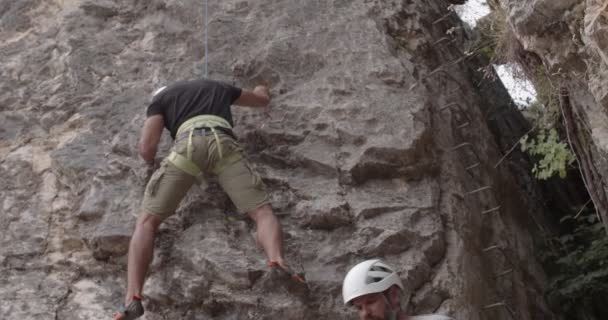 Handsome Fit Guy Climbing Big Rock While His Senior Friend — Vídeo de Stock