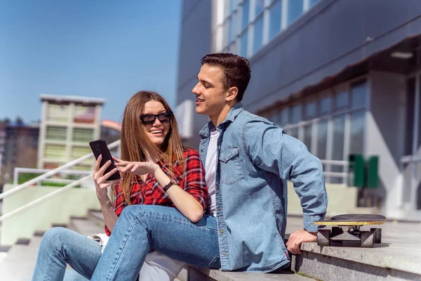 Ragazza Carina Mostrando Qualcosa Suo Ragazzo Telefono Mentre Seduto — Foto Stock