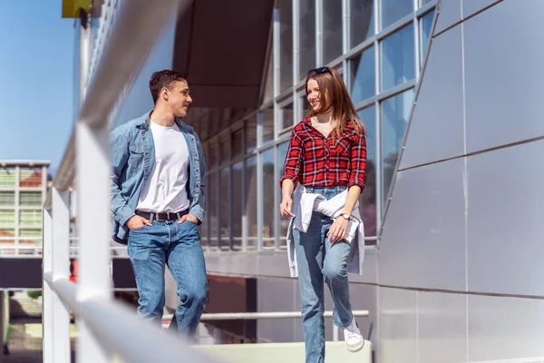 Pretty couple walking in front the building while looking at eachother