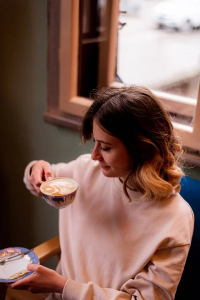 カフェに座っている間に素晴らしい女の子がコーヒーを飲む — ストック写真