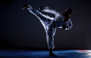 An athlete with a blue belt and in karate performs a formal karate exercise clipart