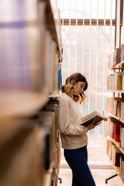 College Mädchen Liest Ein Buch Während Sie Der Bibliothek Steht — Stockfoto