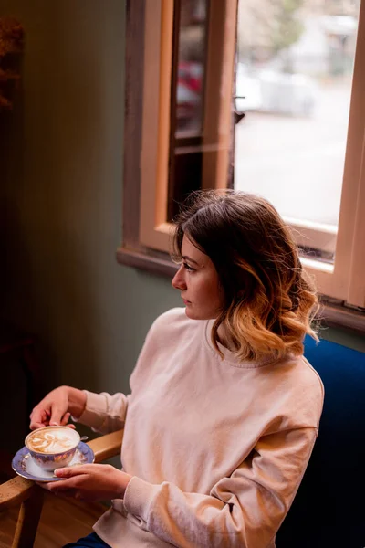 カフェでコーヒーを飲みながら見ている女の子 — ストック写真