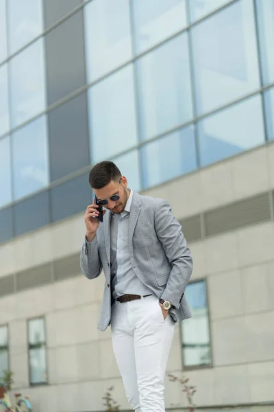 Urban businessman is talking on the phone with his partners