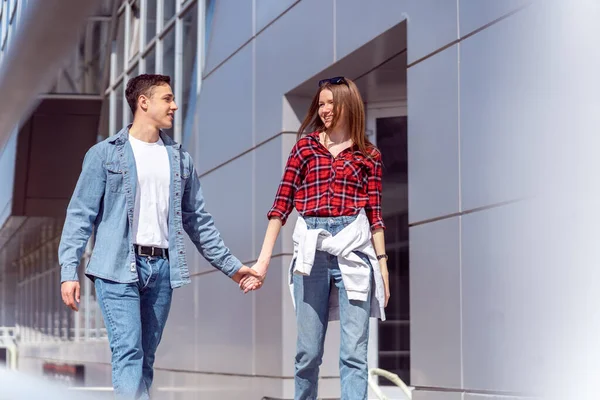 Cute couple walking in front the building while holding hands