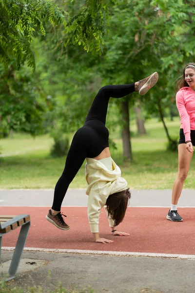 One Attractive Girl Stretching Bending While Other One Watching Her — Stock Photo, Image