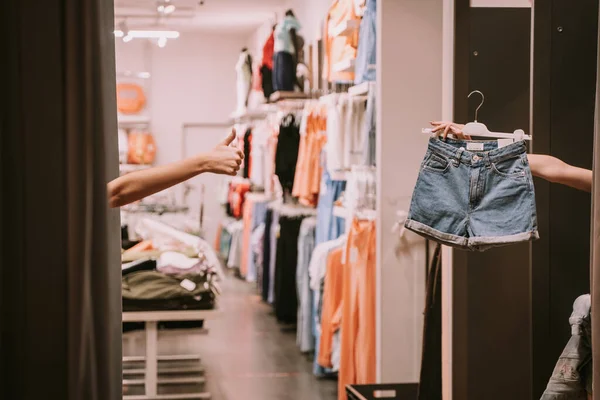 Two girls in the changing room one of them showing the shorts the other one liking them