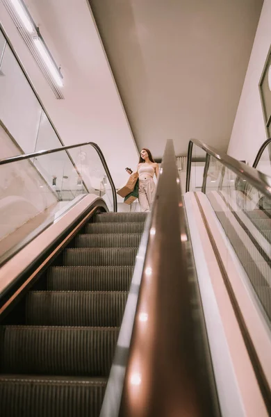 在商场的自动扶梯上 年轻快乐而兴奋的女孩走下楼去 — 图库照片