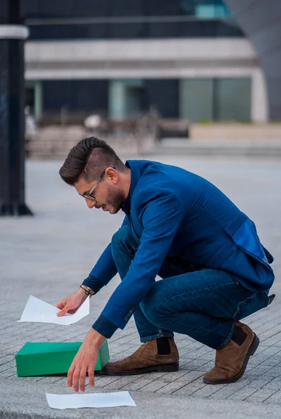 Young urban businessman professional collects documents from the floor