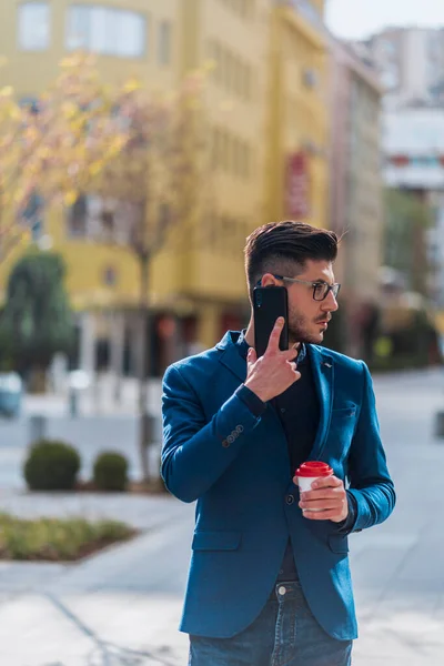 Moda Işadamı Elinde Kahveyle Şehir Meydanında Yürüyor Cep Telefonuyla Konuşuyor — Stok fotoğraf