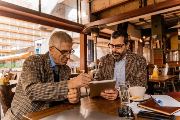 Δύο Ανώτεροι Επιχειρηματίες Συζητούν Έγγραφα Μαζί Ενώ Κάθονται Στο Καφέ — Φωτογραφία Αρχείου