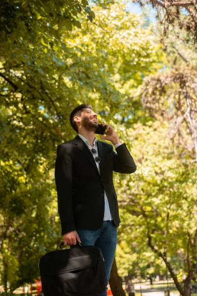 Junger Gutaussehender Geschäftsmann Telefoniert Und Lacht Während Eine Aktentasche Park — Stockfoto