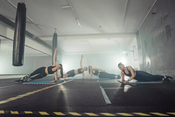 Women in black and white sportswear on a real group body Combat workout in the gym train to fight, kickboxing with a trainer.