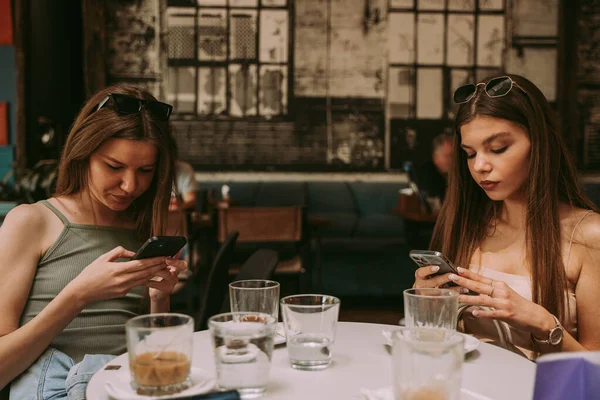 Zwei Schöne Mädchen Die Café Auf Ihren Telefonen Sms Schreiben — Stockfoto