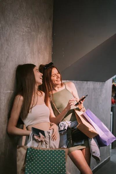 Two Young Beautiful Sisters Laughing Phone Whilst Holding Bags Clothes — Foto Stock