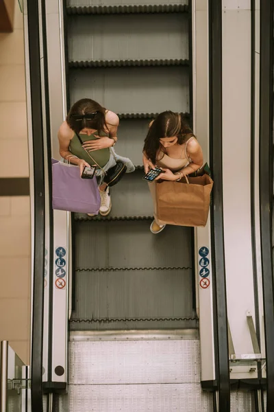 Two Amazing Girls Looking Phones While Going Escalator — Stockfoto