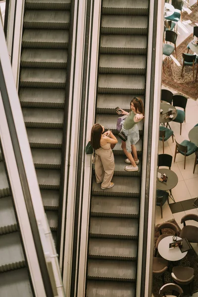 Two Pretty Teenage Girls Going Escalator City Mall While Holding — Stockfoto