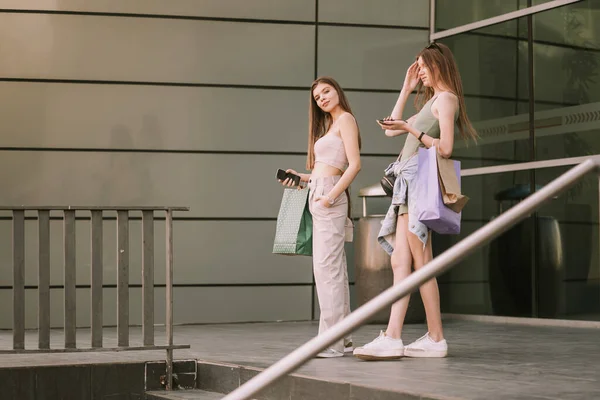 Две Симпатичные Девушки Своими Сумками Стоят Возле Торгового Центра — стоковое фото